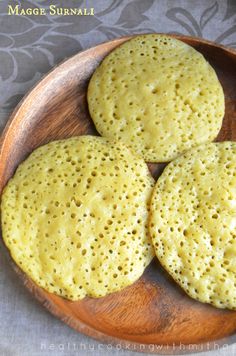 three flat breads on a wooden plate sitting on a tablecloth covered table cloth