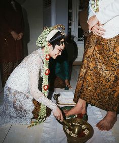 a woman in traditional garb is serving food from a bowl on a table with other people around her