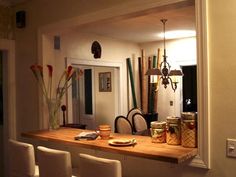 there is a counter with some food on it in the kitchen and two white chairs