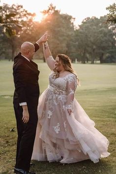 a bride and groom dancing together in the grass at their wedding reception on a golf course