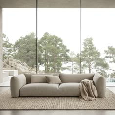 a couch sitting on top of a rug in a living room next to large windows