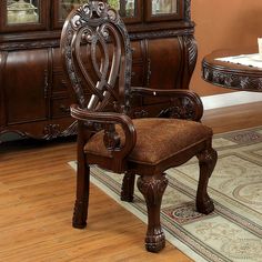 an ornately carved arm chair sits in front of a dining room table and china cabinet