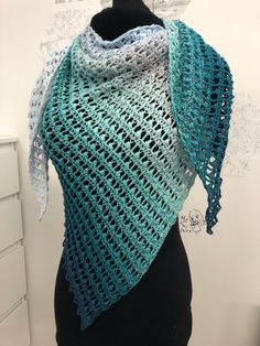 a crocheted shawl is shown on a mannequin