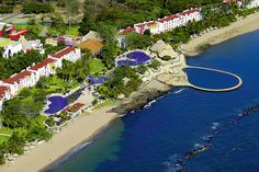 an aerial view of the resort and its surrounding grounds, with blue water in the foreground