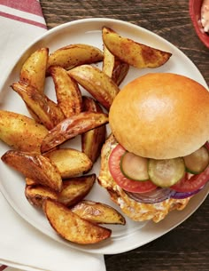 a white plate topped with a burger and fries next to a bowl of pickles