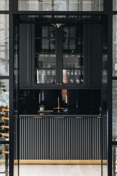 a kitchen with black cabinets and glass doors