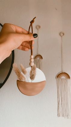 a person is holding a small white object with feathers hanging from it's side