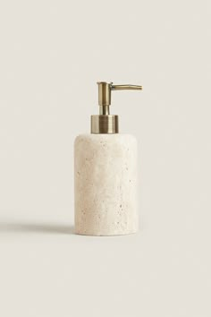 a white soap dispenser with a gold faucet on the top