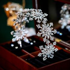 two silver tiaras sitting on top of a wooden box