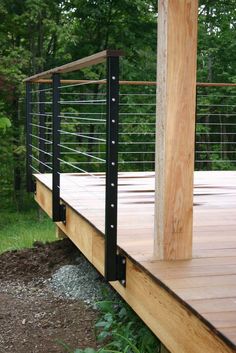 a wooden deck with metal railings in the woods