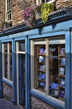 a row of bookshelves on the side of a building with flowers growing out of them