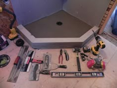 tools are laid out on the floor in front of a shower