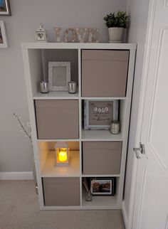 a white book shelf filled with lots of boxes and lights next to a door in a room