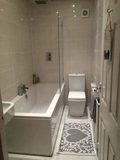 a bathroom with a toilet, bathtub and rug