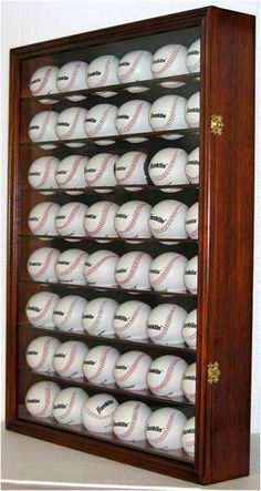 a baseball display case filled with lots of white baseballs on top of wooden shelves