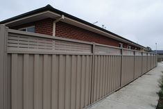 a building that has a fence in front of it and a sidewalk next to it