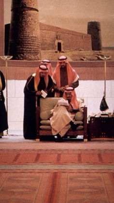 three men sitting on chairs in front of a painting