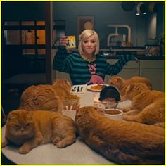 a woman sitting at a table surrounded by cats