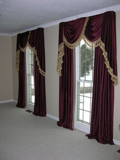 an empty room with two windows and curtains