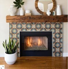 a living room with a fireplace, mirror and potted plants on the mantel