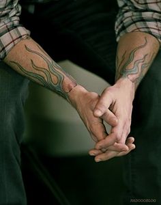 a man holding the hand of another person with tattoos on their arms and hands,