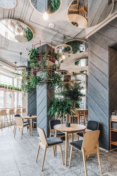 the interior of a restaurant with tables, chairs and potted plants hanging from the ceiling