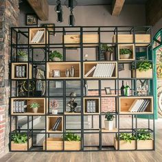 the shelves are filled with books, plants and other decorative items on display in front of a brick wall