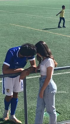 a man and woman standing next to each other on a soccer field