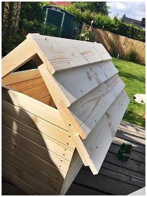 a wooden structure sitting on top of a wooden deck next to a green yard and fence