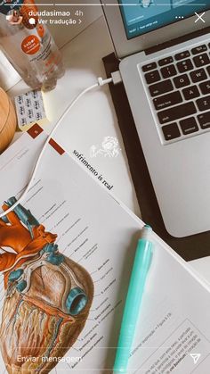 an open laptop computer sitting on top of a desk next to a human heart diagram