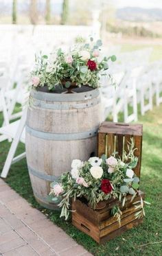 two wooden barrels with flowers and greenery are sitting on the grass next to each other