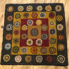 a multi colored area rug with circles and squares on the center in black, yellow, red, green, orange and brown colors