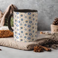 a blue and white coffee mug sitting on top of a table next to cinnamon sticks