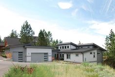 a large house sitting on top of a lush green field next to tall grass and trees