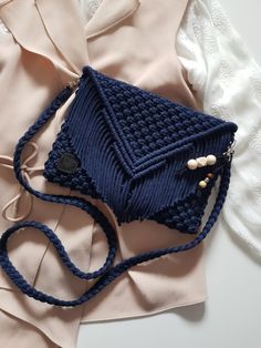 a blue crocheted purse sitting on top of a white table next to a pink shirt