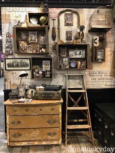 an old fashioned desk in front of a wall with pictures and other items on it