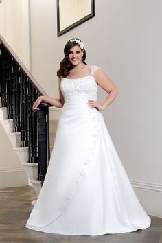 a woman in a white wedding dress standing next to a stair case with her hands on her hips