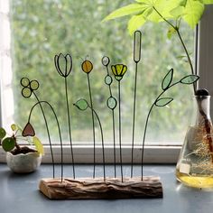 some plants are sitting on a window sill near a vase with flowers in it