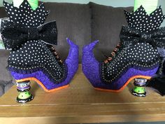 two decorated shoes sitting on top of a wooden table next to a gray couch with black polka dots