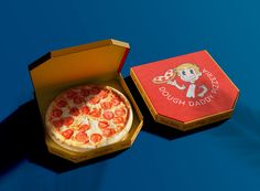 a small pizza in a box on a blue surface with the lid open to show it's contents