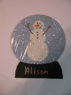 there is a snow globe with a snowman on it and name written in black