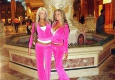 two women in pink outfits standing next to each other near a fountain and marble pillars