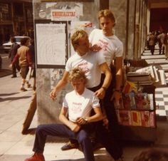 three young men posing for a photo in front of a store