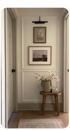 a vase with white flowers sitting on top of a wooden table next to a doorway