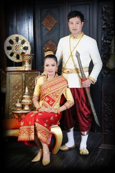 a man and woman in traditional thai garb standing next to each other, posing for a photo