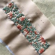 a piece of fabric with flowers on it and some thread in the middle that has been stitched together