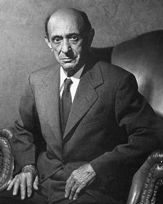 an old black and white photo of a man in a suit sitting on a chair