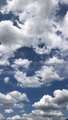 the airplane is flying high in the blue sky with white clouds above it on a sunny day