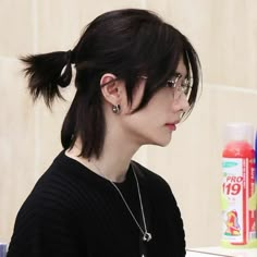 a woman with black hair and glasses is looking at her cell phone while sitting in front of a counter