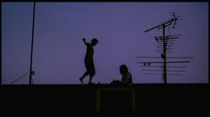 two people standing on top of a roof next to a cell phone tower at night